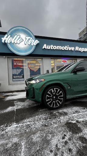 A green BMW SUV parked in the snow in front of Hello Tire