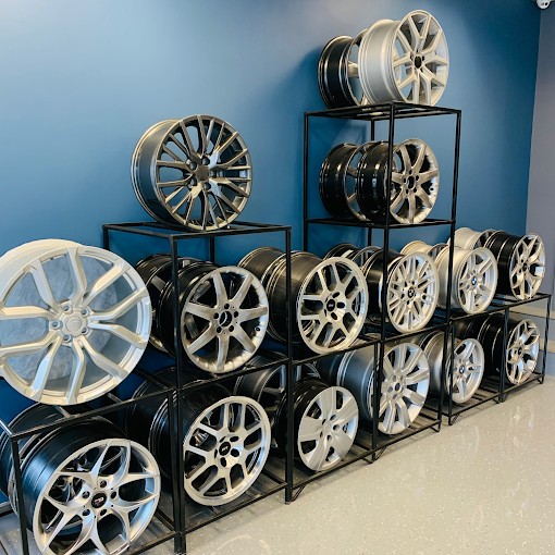 Alloy wheels on black display racks against a blue wall