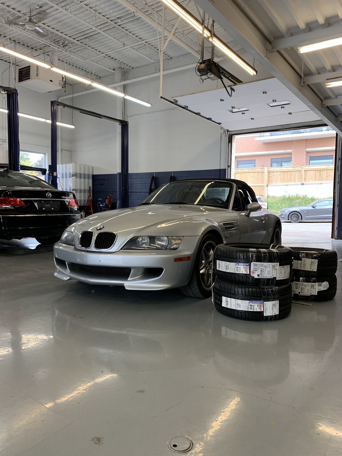 A silver BMW roadster in the Hello Tire bay beside a stack of new Michelin tires
